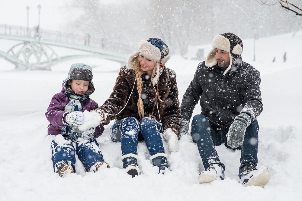 image f a man, a woman and a child sitting in the snow