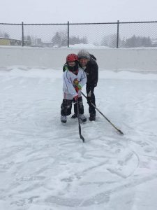 image of father and son on the community rink with hockey sticks at the Carnival