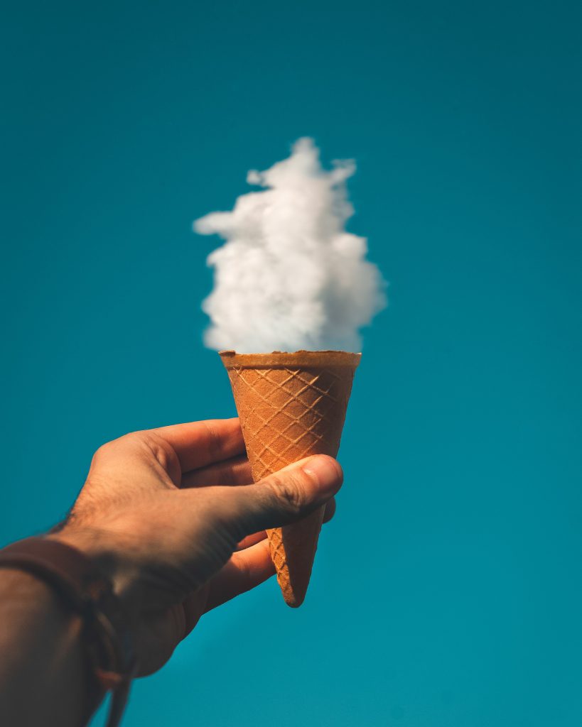 photo of someone holding an ice cream cone up to the sky with a cloud looking like the ice cream in the cone.