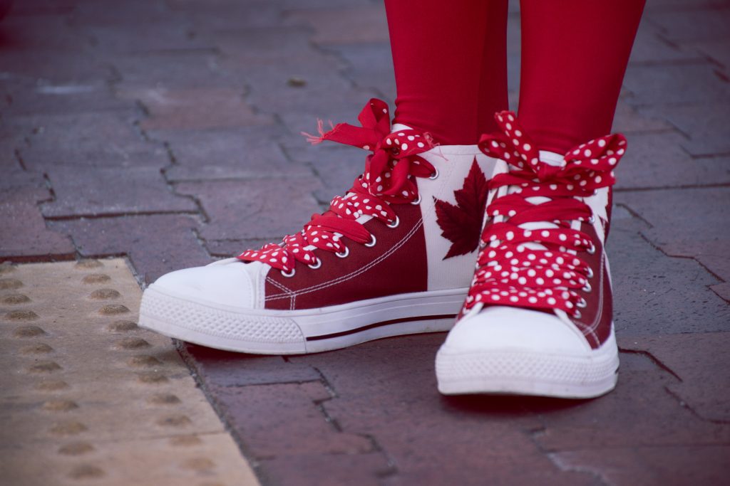 someone wearing red and white sneakers with canada flags on them