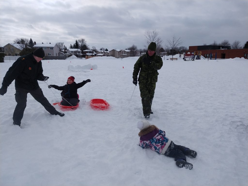 people playing in the snow with sleds