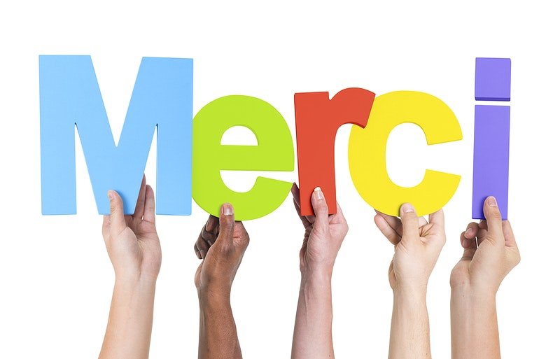 people holding up letters that spell MERCI