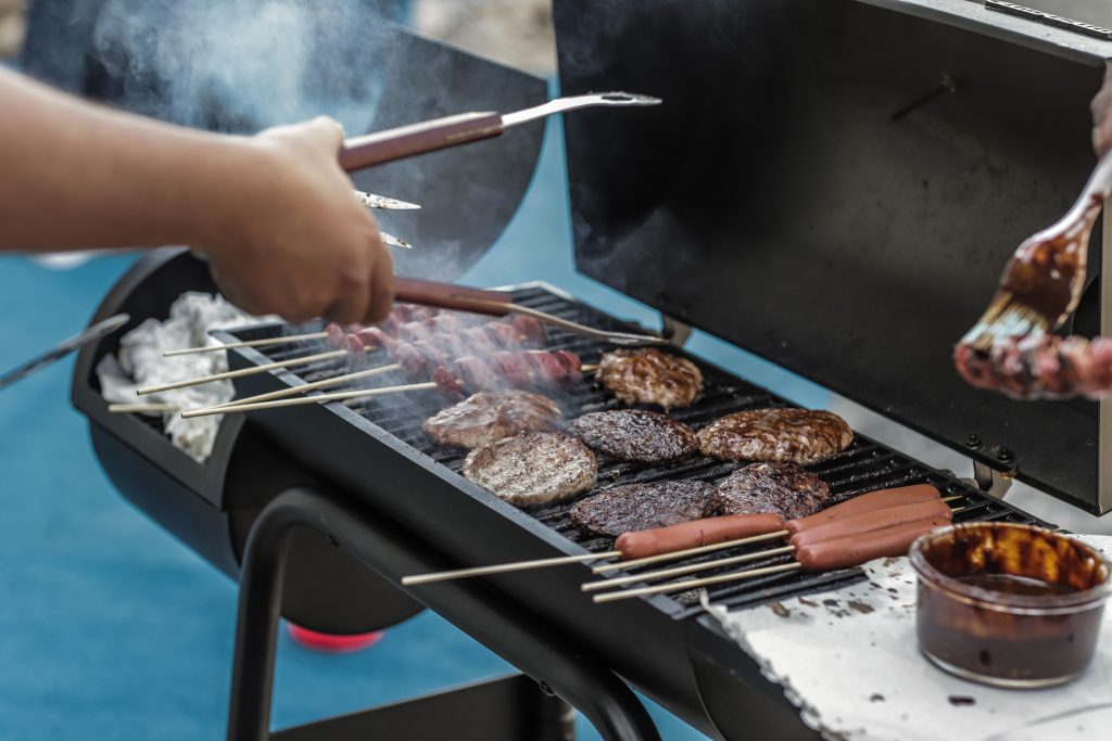 person grilling burgers and hot dogs