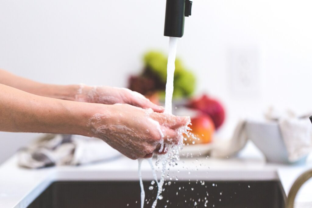 person washing their hands at the kitchen sink