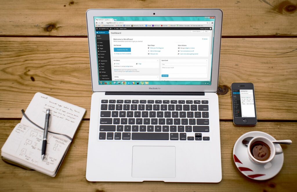 photo of a computer, notebook and coffee on a table