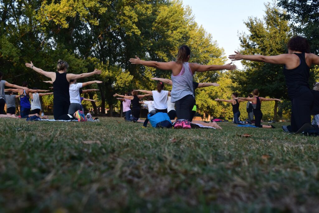 a group of people doing a yoga class outside in a park