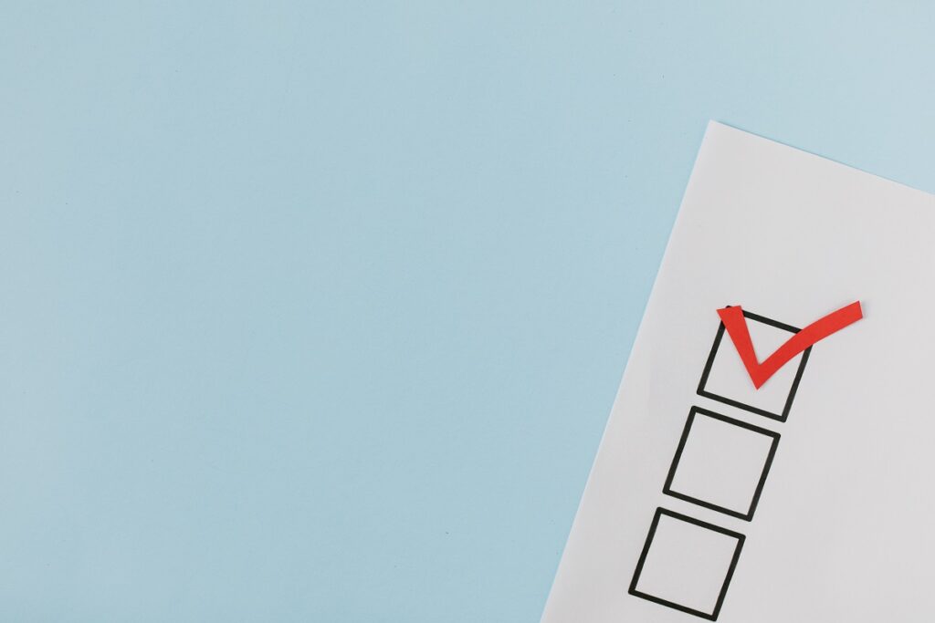 a blue background with a white page on it. The white page has three black boxes and one box has a red check mark in it to indicate a vote.