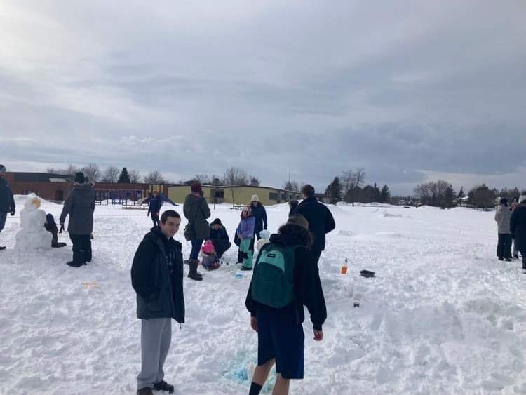 a wide photo of about 20 people enjoying the outdoors and the games in the snow at the winter carnival / une grande photo d'environ 20 personnes profitant du plein air et des jeux dans la neige lors du carnaval d'hiver