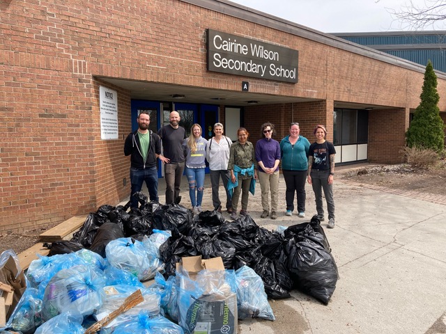 8 community members who are part of the Environment Committee standing with the enormous pile of garbage and recycling that they gathered during the CGOWCA Cleaning the Capital event on Earth Day.
