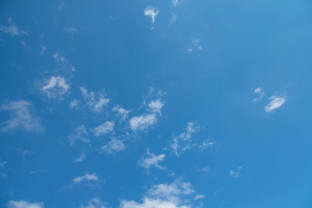 a photograph of the blue sky with a few scattered white clouds dotting the blue.